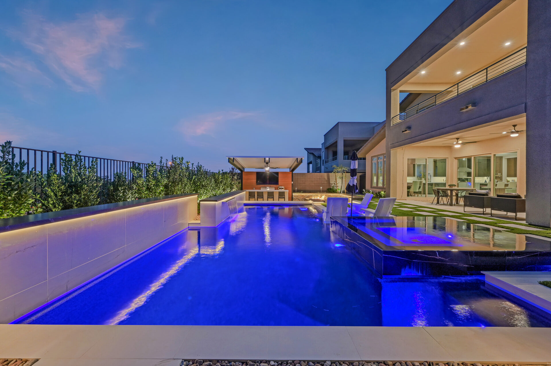 Backyard with sunken fire pit lounge and elevated black marble spa at dusk