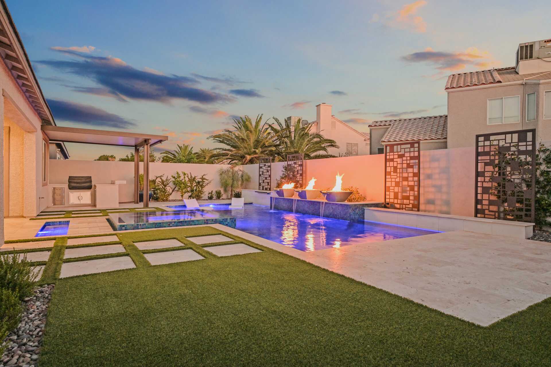 Backyard at dusk with triple fire-and-water bowls and geometric laser-cut screens