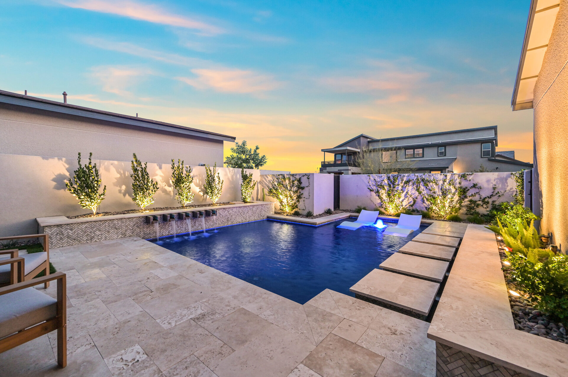 Compact backyard pool with herringbone water feature wall and floating loungers